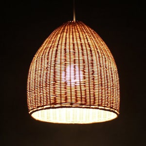 May include: A woven wicker pendant light fixture with a warm, yellow glow emanating from the bulb inside.