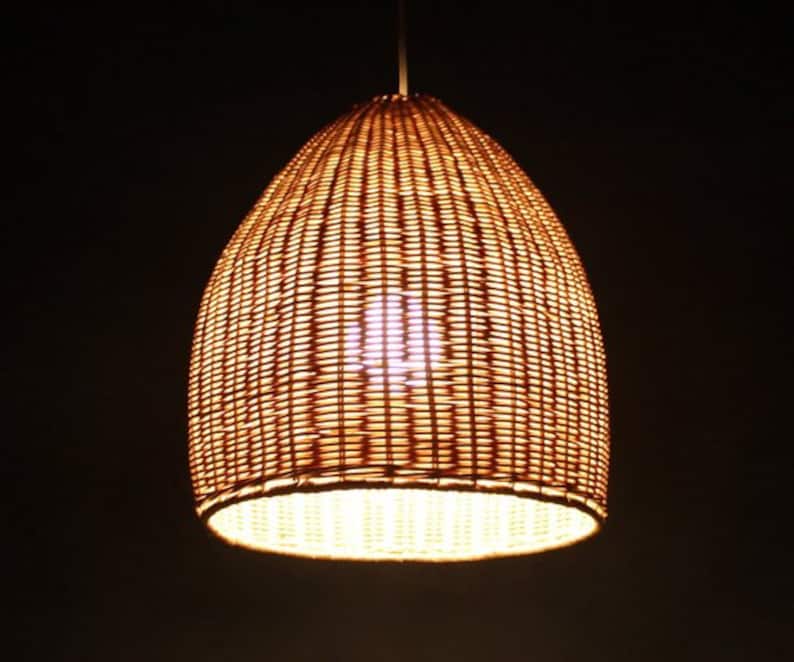 May include: A woven wicker pendant light fixture with a warm, yellow glow emanating from the bulb inside.