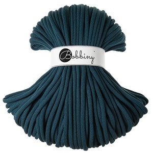 May include: A teal blue cotton cord, wound into a circle, with a white label that reads "Bobbiny".
