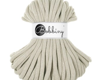 May include: A skein of light beige cotton rope, labeled "Bobbiny" in black text on a white label.