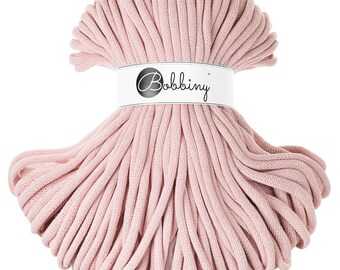 Op de afbeelding: Een close-up van een roze katoenen touw, opgerold in een cirkel, met een wit label waarop "Bobbiny" staat.