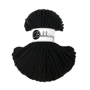 Puede incluir: Madeja de cordón de macramé negro con motas de color. El cordón está envuelto con una etiqueta blanca que dice "Bobbing" en cursiva. El cordón está bien enrollado y tiene un aspecto texturizado.