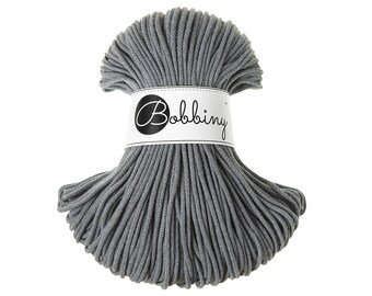 Puede incluir: Un cordón de algodón gris, enrollado en un círculo, con una etiqueta blanca que dice "Bobbiny" en letras negras.