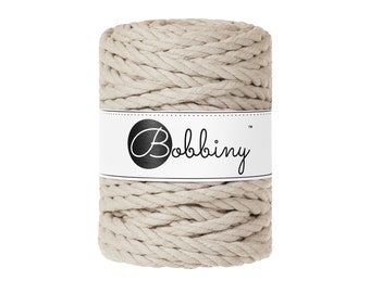 May include: A beige spool of cotton rope with the brand name "Bobbiny" printed on a white label.