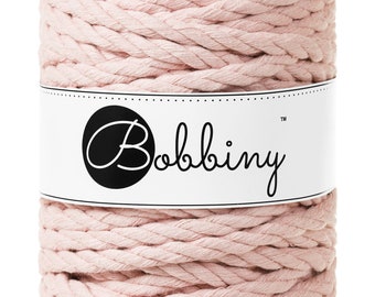 Op de afbeelding: Een rol roze katoenen touw met een wit label waarop "Bobbiny™" staat.