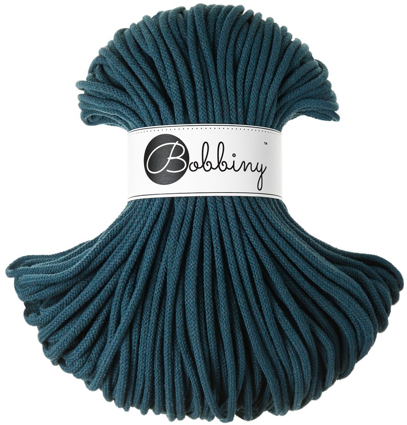 May include: Teal cotton cord, a thick, twisted rope, is wound into a circle. The cord is labeled "Bobbiny" on a white tag.