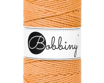 May include: A spool of orange cotton rope with the brand name "Bobbiny" printed on a white label.