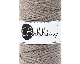 Op de afbeelding: Een rol lichtbruin katoenen touw met een wit label waarop "Bobbiny™" staat.