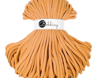 Op de afbeelding: Een spoel met dikke, oranje katoenen koord, met het label "Bobbiny".