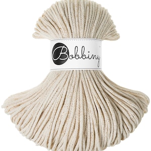 Op de afbeelding: Een close-up van een beige katoenen touw met een wit label waarop "Bobbiny" staat.