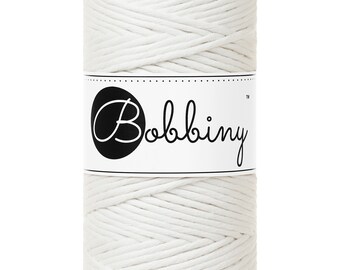 Könnte beinhalten: Eine weiße Rolle aus Baumwollschnur mit dem Text "Bobbiny™" auf einem weißen Etikett.
