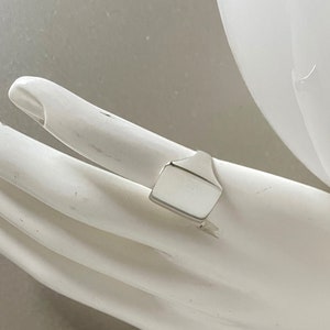 May include: A silver signet ring with a rectangular top.