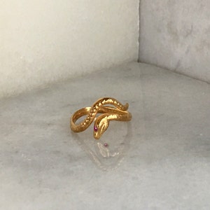 May include: A gold snake ring with a pink stone for an eye.