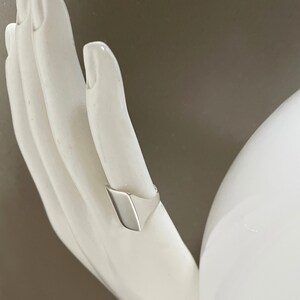 May include: A silver signet ring with a flat, rectangular top.