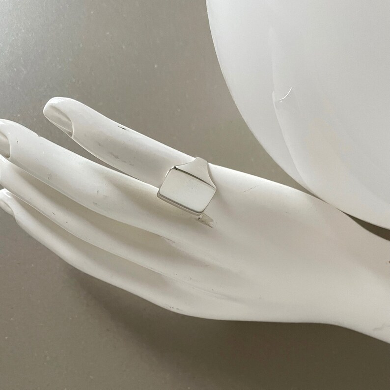 May include: A silver signet ring with a rectangular top.