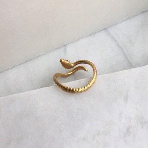May include: A gold snake ring with a blue eye. The snake is curled around the ring band.