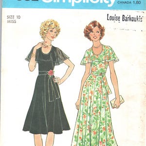 May include: Simplicity pattern envelope featuring two dress designs. One is a black dress with a rose at the waist, and the other is a floral print dress. The envelope includes the text "7382 Simplicity" and "Louise Barkoukis".