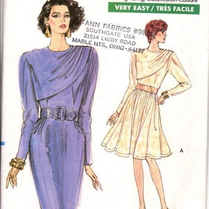 以下が含まれることがあります： Very Easy Very Vogueの型紙封筒7355、サイズ14。長袖のドレス2着のイラストが描かれています。1着はベルト付きの紫色のタイトドレス、もう1着はフレアスカートとベルトが付いたクリーム色のドレスです。