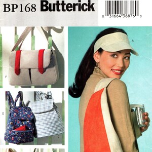May include: Butterick BP168 sewing pattern featuring various bag designs. The image showcases a shoulder bag with a red accent, a floral print bag, a striped tote, and two backpack styles. The pattern includes the text "ONE SIZE/UNE SEULE TAILLE".