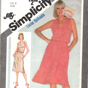 Op de afbeelding: Vintage Simplicity naaipatroon, maat 8, met een vrouw in een koraalkleurige jurk. Het patroon is ontworpen voor stretch breisels. De envelop toont ook een gestreepte jurk. De tekst op de envelop luidt "Simplicity Today".