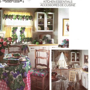 Puede incluir: Una escena de cocina vintage con una mesa decorada con un mantel y cojines de silla adornados con un patrón de uvas y hojas. La imagen también muestra cortinas a juego y un armario con elementos esenciales de cocina. El logotipo de Simplicity House es visible.