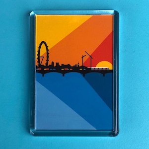 May include: Rectangular magnet featuring a stylized London skyline silhouette against a sunset gradient of yellow, orange, and red. The design includes the London Eye, bridge, and a blue river. The magnet is encased in a clear, rectangular frame.