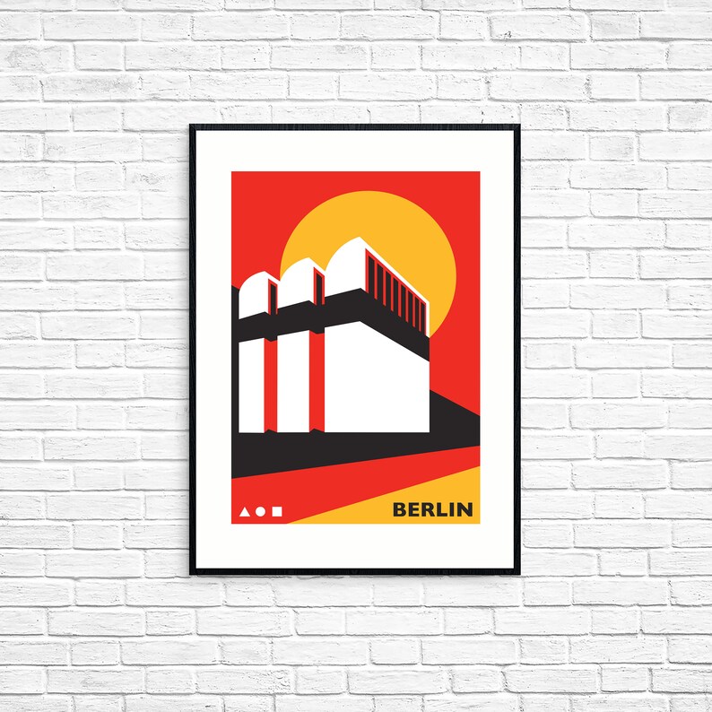 Op de afbeelding: Ingelijste kunstdruk met een geometrische illustratie van een gebouw in Berlijn. Het kunstwerk gebruikt een gedurfd kleurenpalet van rood, zwart, wit en geel. Het woord "BERLIJN" staat in het wit onderaan de afbeelding.