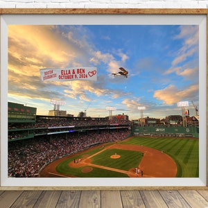 May include: A photograph of Fenway Park in Boston, Massachusetts, with a banner that reads "Boston Celebrates Ella & Ben October 9, 2024" being flown by a small plane over the stadium.