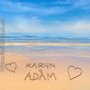 May include: A sandy beach with blue sky and ocean in the background. The words "KARYN + ADAM" are written in the sand with a heart on either side.