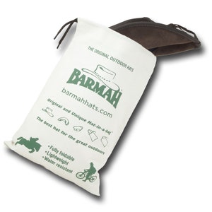 May include: A white canvas bag with a brown hat inside. The bag has the text "THE ORIGINAL OUTDOOR HATS" and "BARMAH barmahhats.com" printed on it. The bag also has the text "Original and Unique Hat-in-a-bag" and "The best hat for the great outdoors" printed on it. The bag has a green logo of a hat with the text "BARMAH" printed on it. The bag also has the text "Fully foldable", "Lightweight", and "Water resistant" printed on it.