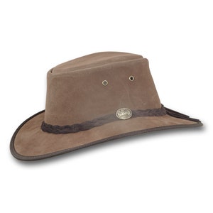 May include: A brown suede hat with a wide brim and a braided band. The hat features a metal emblem and eyelets on the crown. The hat is designed for outdoor wear.