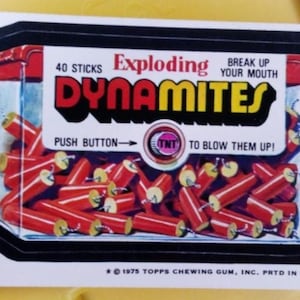 May include: A vintage sticker featuring a box of red dynamite sticks. The label reads "Exploding Dynamites" in red and yellow text. The text "Break up your mouth" is also visible. The sticker includes the text "Push Button to Blow Them Up!"