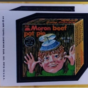 May include: A vintage Topps chewing gum sticker with a cartoon boy wearing a blue and white hat, with the words "Moron beef pot pie." The sticker also includes the text "Rejected US Dept of Culture" and "Net Wt 227g."