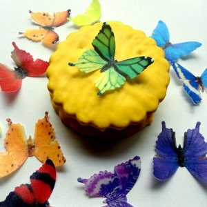 May include: A yellow cake with colorful butterfly decorations. The butterflies are made of edible paper and come in a variety of colors, including red, orange, yellow, green, blue, and purple.