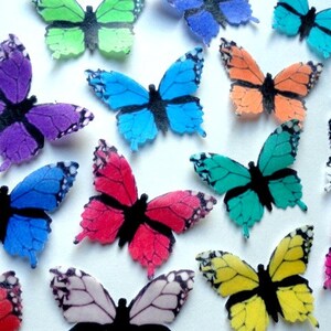 May include: Assortment of colorful butterfly cake toppers. The butterflies are made of edible wafer paper and come in a variety of colors, including blue, green, purple, red, yellow, and orange. The butterflies have black wings and bodies.