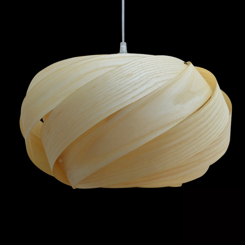 May include: A light wood pendant lamp with a unique, swirling design. The lampshade is made of thin strips of wood that are woven together to create a modern and organic look.