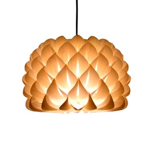Könnte beinhalten: Eine Holz-Pendelleuchte mit einem einzigartigen Design, das an eine Blume erinnert. Die Leuchte besteht aus vielen dünnen, überlappenden Holzstücken, die ein filigranes und komplexes Muster bilden. Die Leuchte ist beleuchtet und strahlt ein warmes Licht aus.