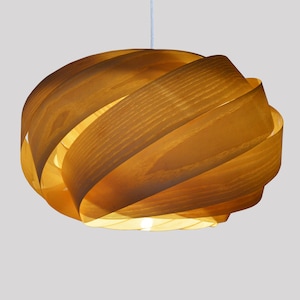 May include: A wooden pendant light fixture with a unique, swirling design. The light is made of thin, layered strips of wood that create a warm, natural look.
