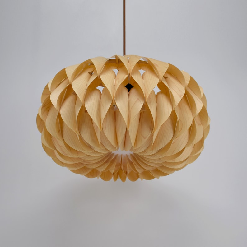 May include: A light wood pendant lamp with a unique, organic design. The lampshade is made of thin, curved pieces of wood that create a flower-like shape.