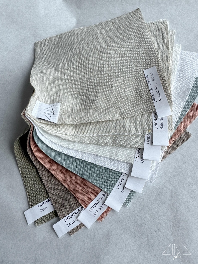 Puede incluir: Una colecci&oacute;n en abanico de muestras de tela de lino cuadradas en varios colores, incluyendo natural, blanco, oliva, topo, arena rosada e iris. Cada muestra tiene una etiqueta blanca con texto como LINONATA 300 gsm, Natural Flax, 300 cm.