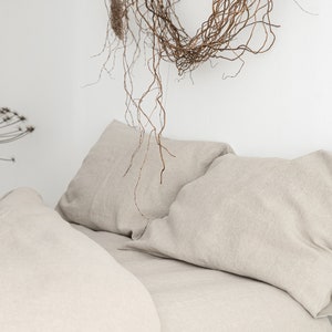 Puede incluir: Primer plano de una cama con dos almohadas de lino beige y una funda n&oacute;rdica de lino beige. La cama est&aacute; hecha con tejido de lino fresco y sin arrugas.