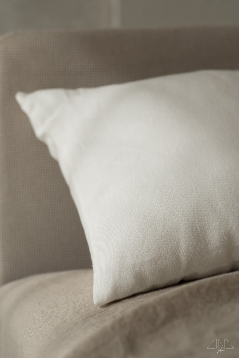 May include: A white linen pillow resting on a beige linen bedspread.