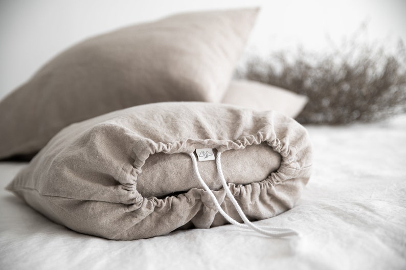 May include: A beige linen pillowcase with a drawstring closure and a white label with the text "Linen & Love" on it.