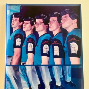 May include: A vintage poster featuring the band Devo. Five men in blue shirts with white collars and white pants stand in a row. The shirts have the words "New Traditionalists" on the sleeves. The band's name "DEVO" is printed in large red letters at the bottom of the poster.