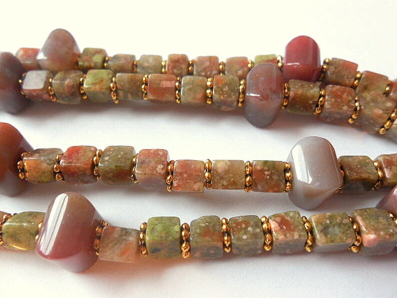 May include: A multi-strand necklace made with brown, green, and pink gemstone beads. The beads are separated by small gold beads.