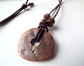 Bronze patina Greek ceramic disk pendant on adjustable leather cord.