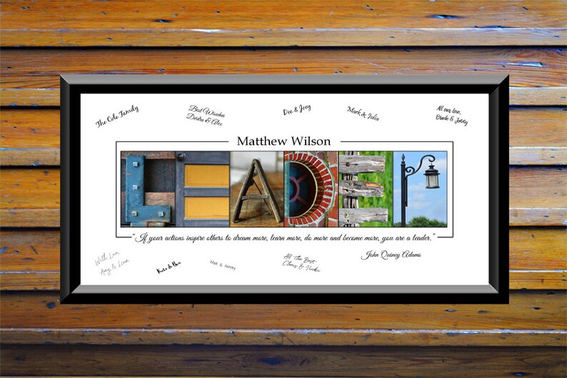 May include: A framed print featuring the word "LEADER" spelled out in colourful letters made from various textures and materials. The quote "If your actions inspire others to dream more, learn more, do more and become more, you are a leader." by John Quincy Adams is printed below the letters. The print is signed by several people.