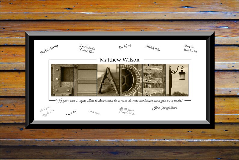 May include: A framed print featuring a sepia-toned photograph of the word "Leader" spelled out using various rustic textures. The quote "If your actions inspire others to dream more, learn more, do more and become more, you are a leader." by John Quincy Adams is printed below the photo. Several signatures are visible on the print.
