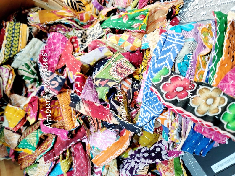 May include: A pile of colorful fabric scraps, some with floral patterns, others with geometric designs. The scraps are arranged in a random order, creating a visually appealing and textured composition.  The text "Amour Fabrics" is visible on some of the scraps.