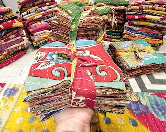 May include: A stack of colorful fabric squares tied with a ribbon. The fabric squares are made of kantha, a type of Indian hand-stitched quilting.